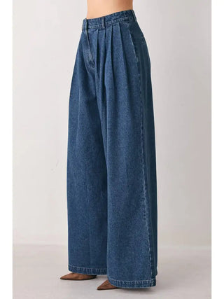 Medium blue wash wide leg denim jeans with pleated front detail and high waist silhouette.