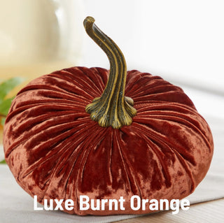 Large burnt orange velvet pumpkin with realistic dark green curved stem, plush ribbed fabric texture, fall décor.