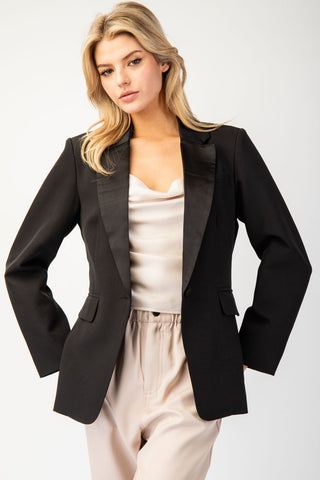Black long sleeve blazer jacket with satin lapel collar, worn open over cream satin top.