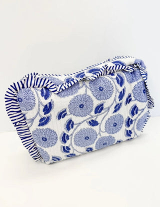Quilted cosmetic bag in white with blue floral embroidery and striped ruffle trim, structured rectangular shape.