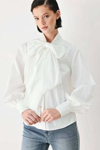 White long-sleeve woven blouse with oversized bow tie neck detail and ruffled cuffs.