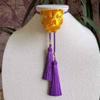 Gold bulldog head bolo tie necklace with crystal eyes and cascading double deep purple tassels on purple cord.