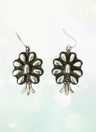 Burnished silver squash blossom dangle earrings with floral petal design and decorative dotted detailing.