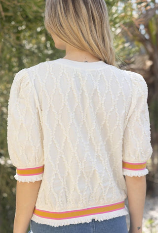 Cream diamond textured puff sleeve top with pink and mustard striped elastic hem and cuffs.