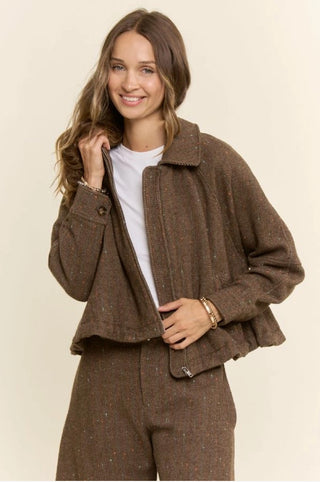 Brown herringbone tweed zip-front bomber jacket worn over white tee with matching trousers.
