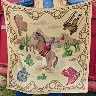 Cream western bandana featuring cowgirl on rearing horse, cacti, cowboy hat, red boots, and decorative rope border.