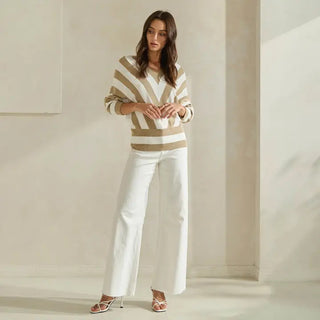 Beige and white striped dolman sleeve sweater top paired with wide-leg white jeans and strappy heels.