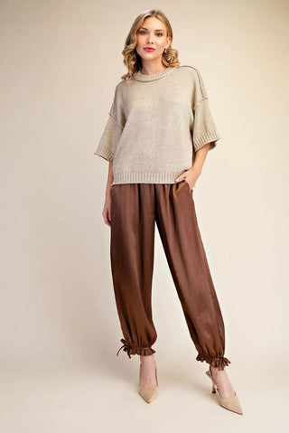 Oversized beige lurex metallic knit sweater with short sleeves and ribbed hem, styled with brown satin pants.
