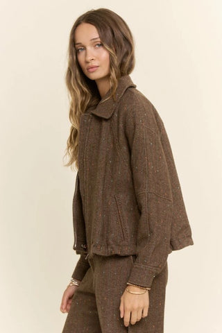 Brown herringbone tweed zip-front bomber jacket with spread collar and speckled texture, styled as a matching set.