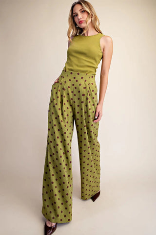 Olive green wide-leg pleated trousers with brown polka dots, high-waisted, paired with matching sleeveless top.