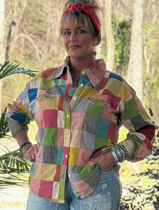Woman wearing colorful patchwork button-up shirt featuring multicolor squares in pink, green, blue, yellow, and gray.