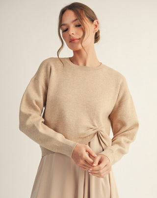 Beige long sleeve knit sweater with drop shoulders and side knot accent detail, worn by model.