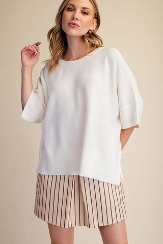 White oversized pullover sweater with short sleeves, ribbed hem and cuffs, relaxed boxy fit.