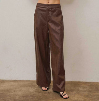 Brown wide-leg vegan leather pants with mid-rise waist, styled with black strappy sandals.
