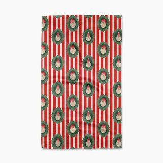 Red and white striped tea towel featuring repeated Santa Claus faces framed in green wreaths.