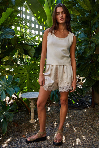 Beige satin mini shorts with floral lace trim hem, worn with matching knit tank top and sandals.