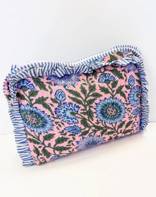 Quilted pink cosmetic bag with blue floral print and blue striped ruffle trim closure.