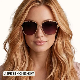 Women's oversized square gold-frame sunglasses with gradient smoky brown lenses, modeled by blonde woman.