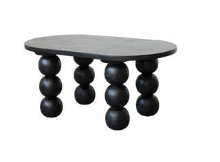Black mango wood coffee table with rounded oblong top and stacked spherical orb legs.
