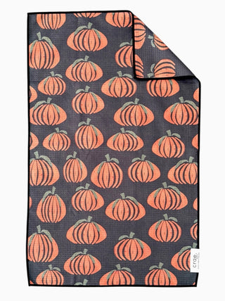 Dark gray waffle-weave hand towel featuring an allover orange pumpkin print with green stems, folded corner detail.