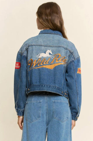 Blue denim jacket with gold "Wild Ride" embroidery, white horse graphic, and Western rodeo patches on sleeves.