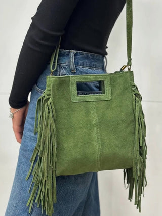 Green suede fringed crossbody bag with rectangular top handle and long tassel fringe detail on sides.