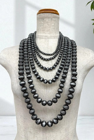 Multi-strand layered Navajo pearl necklace featuring graduated dark silver beads on a mannequin display.