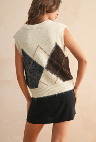 Cream argyle sweater vest with charcoal and brown diamond pattern, worn over black mini skirt.