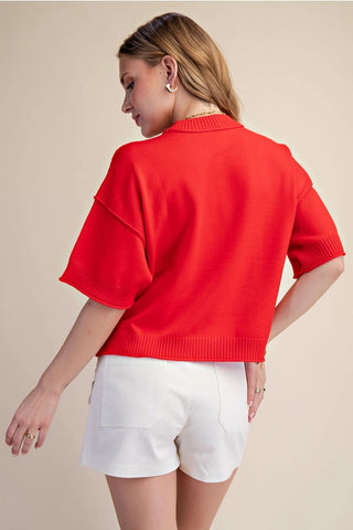Red knit sweater with elbow-length sleeves and seam detail, paired with white shorts, back view.
