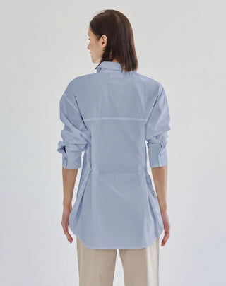 Light blue oversized button-down shirt with single pocket, long sleeves, and relaxed fit, back view.
