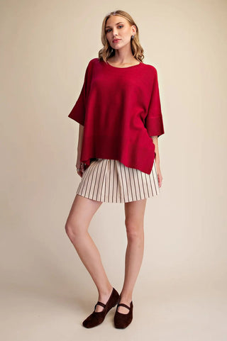 Red oversized round neck short sleeve pullover sweater styled with striped cream mini shorts and brown Mary Jane flats.