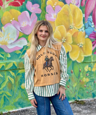 Mustard yellow boxy crop tank top with "Hold Your Horses" graphic print, layered over green striped shirt.