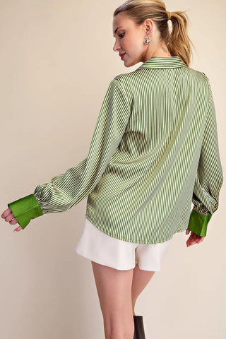 Green and white striped satin button-down shirt with solid green cuffs and V-neck collar, worn with white shorts.