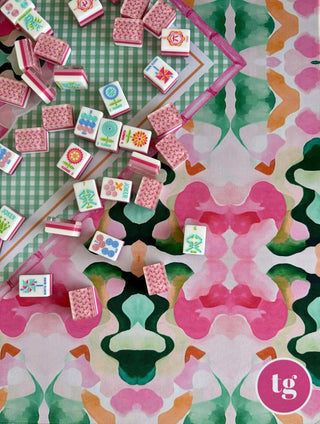 Pink and green floral Royal Garden mahjong mat with scattered pink-backed mahjong tiles and rack.