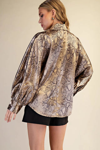 Woman wearing oversized gold metallic snake print blouse with voluminous sleeves and button-front collar.