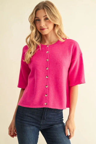 Hot pink drop shoulder short sleeve button-front cropped sweater with round neckline, paired with dark jeans.