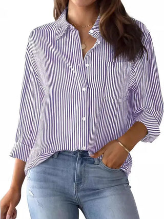 Purple and white striped button-down shirt with chest pocket, worn open collar, long sleeves, paired with jeans.