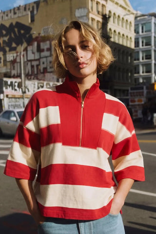Red and cream wide-stripe pullover top with gold half-zip neckline and three-quarter sleeves.