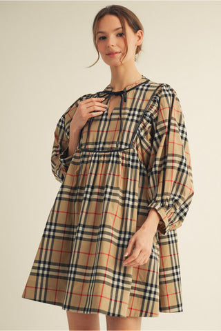 Tan plaid babydoll dress with black leather trim, tie neckline, and 3/4 puff sleeves.