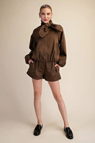 Brown scarf collar front zip puffy jacket worn with matching shorts and black loafers.