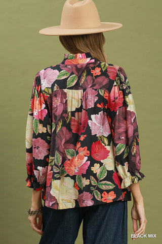 Black floral print button-front blouse with pink, red, and green flowers, ruffled sleeve cuffs, back view.