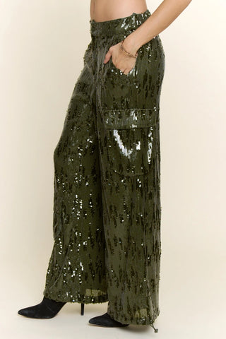 Olive green wide-leg sequin cargo pants with side pocket, worn with black heeled boots.