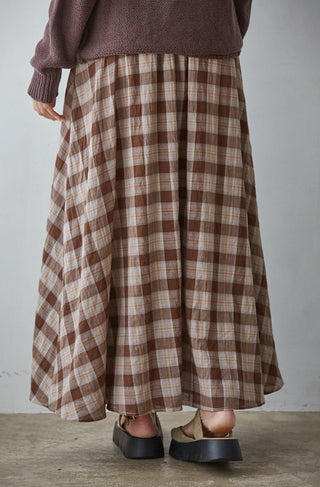 Brown and beige plaid flare midi skirt with gathered waist, paired with dark platform sandals.