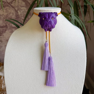 Purple bulldog head bolo necklace with golden yellow cord and two lavender tassel pendants displayed on jewelry bust.