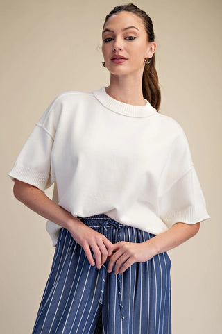 White knit sweater with elbow-length sleeves, ribbed cuffs and neckline, and subtle seam detail.