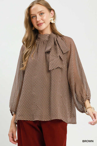 Brown polka dot chiffon blouse with tie neck ruffle detail and billowy long sleeves.