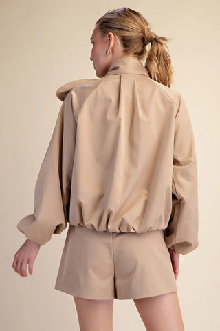 Beige faux leather puffy jacket with scarf collar, balloon sleeves, and elasticated hem, worn with matching shorts.