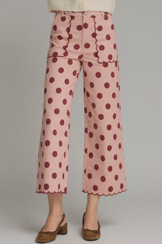 Pink wide-leg cropped pants with burgundy polka dots, scalloped waistband, pockets, and hem trim detail.