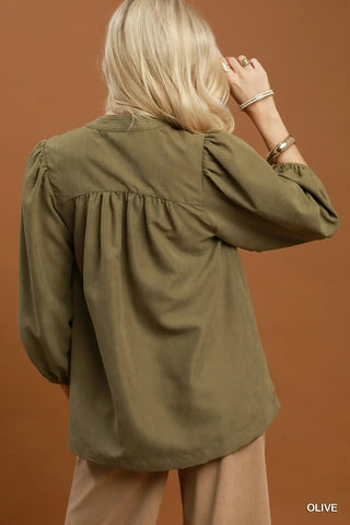 Olive green sueded split neck blouse with gathered back yoke, puff sleeves, and contrast stitching detail.