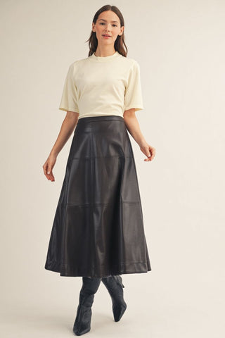 Black vegan leather tiered A-line midi skirt with visible seam detailing, styled with cream top.